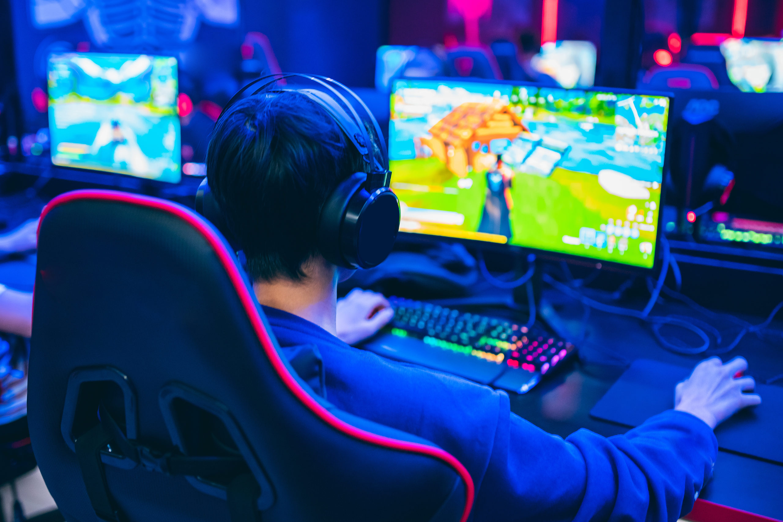 Professional cyber video gamer studio room with personal computer armchair, keyboard for stream in neon color blur background. Soft focus